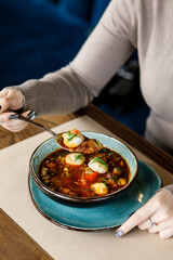 handsome delicious, rich soup with juicy beef, fresh vegetables, and fragrant herbs, served in a beautiful blue bowl on a wooden table in a cozy, charming restaurant