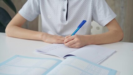 A close-up of a schoolboy's hands with a pen, focused on studying and writing notes