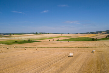 Yellow golden straw bales of hay in the stubble field. Hay bales on agriculture field after harvest on a sunny summer day