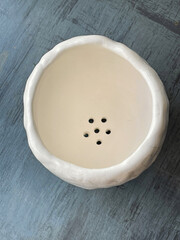 Top view of white handmade glaze ceramic flowerpot on blue background. Empty pot for gardering