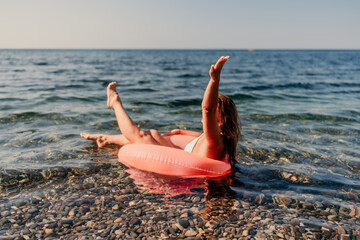 A woman is floating in a red inflatable tube in the ocean