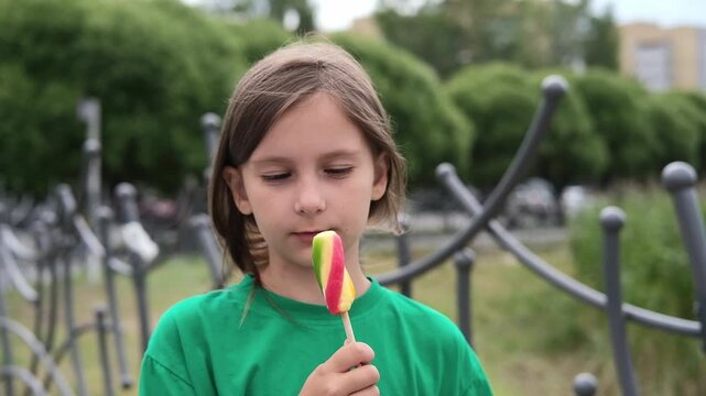Child eats ice cream in summer when outside on sunny summer day. Sweet food on hot summer days. Bright light, colorful ice cream.