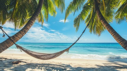 Fototapeta premium Hammock between two palm trees on a quiet tropical beach, with clear blue ocean waves lapping the shore.