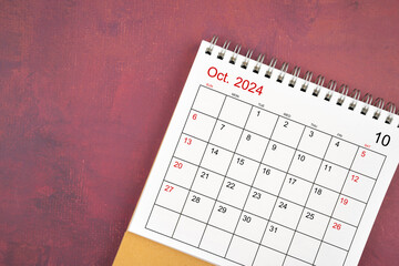 October 2024 desk calendar on red background.