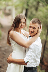 A young couple is embracing each other in a forest