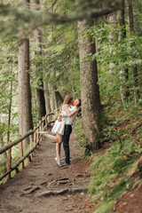 Obraz premium A couple is hugging in a forest, with the man standing behind the woman