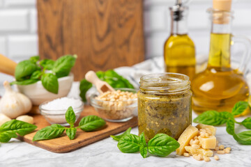 Pesto. Italian basil pesto sauce on a textured wooden background. Ingredient for pesto sauce: fresh basil, pine nuts, Parmesan cheese and olive oil. Space for text.Copy space.