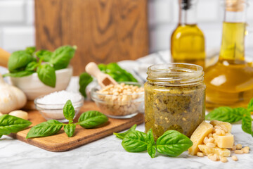 Pesto. Italian basil pesto sauce on a textured wooden background. Ingredient for pesto sauce: fresh basil, pine nuts, Parmesan cheese and olive oil. Space for text.Copy space.