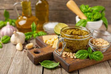 Pesto. Italian basil pesto sauce on a textured wooden background. Ingredient for pesto sauce: fresh basil, pine nuts, Parmesan cheese and olive oil. Space for text.Copy space.