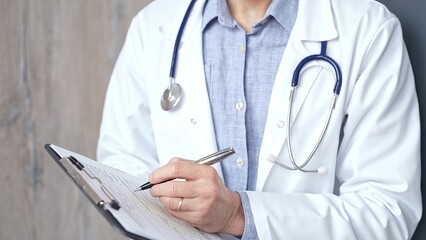 Healthcare professional doctor is focused on updating medical charts on a clipboard. Male unrecognizable physician at work. Medicine and pharmacy