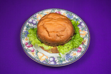 beef cheese burger on a beautiful plate isolated on purple background