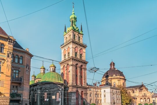 Korniakt Tower, the dome of The Dominican church and the roofs of other ancient buildings in an interweaving of electrical wires against the blue sky in Lviv, Ukraine