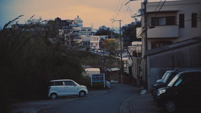 Scenic view of kei cars parked in a residential neighborhood in Saikazaki, Japan during sunset. Calm evening atmosphere in a suburban setting.