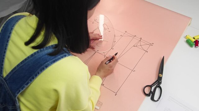 Fashion designer employs an unconventional semicircular template to meticulously craft the intricate curves that will define the silhouette of the upcoming clothing line.