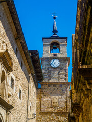  View of Torre del Reloj in Ponferrada, Spain, a historic clock tower rising above a narrow stone...