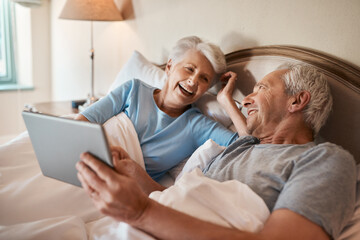 Obraz premium Elderly, couple and laughing with tablet in bedroom for social media, browsing internet and watch videos. Senior people, streaming and home with technology for movie, online entertainment and bonding