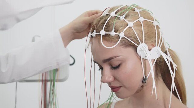 A doctor places EEG sensors on a young patient's head for brain testing in a medical center. Ideal for showcasing advanced diagnostics and professional healthcare settings.