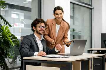 CEO mentoring a trainee on financial operations using a laptop in a modern office. A great shot for showcasing professional guidance and corporate training