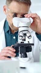 Man scientist with protective glasses using microscope in laboratory. Microbiology science concept