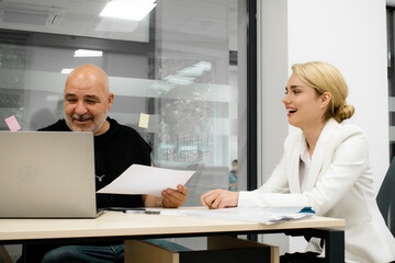 CEO mentoring a trainee on financial operations using a laptop in a modern office. A great shot for showcasing professional guidance and corporate training