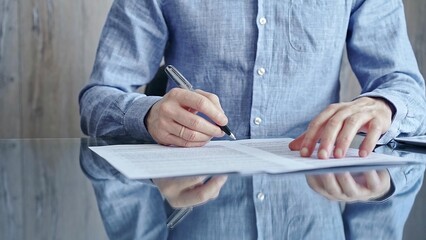 Businessman signing contract at desk. Close-up of a male executive signing a legal document on a...