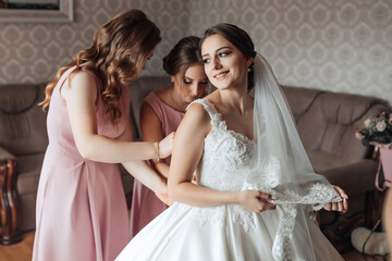 A bride is getting ready for her wedding with her bridesmaids. The bride is wearing a white dress and a veil