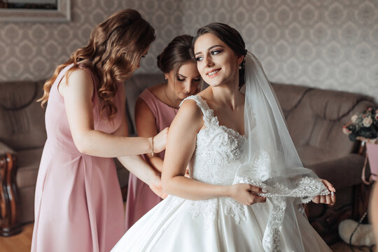 A bride is getting ready for her wedding with her bridesmaids. The bride is wearing a white dress and a veil