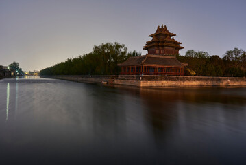 Northeastern tower of the Forbidden City reflecting in the water moat during still night in...