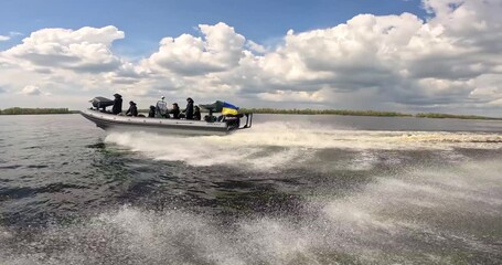 A patrol boat floats along the river against the backdrop of beautiful clouds. The boat is patrolling the river. A fast patrol boat sails along the river.