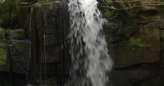Mid shot tilting down of the Lumsdale waterfalls with rocks and trees at Lumsdale, Matlock