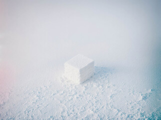 A white cube is sitting on top of a pile of snow