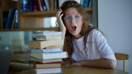 beautiful young woman student in glasses, sitting with books in library. concept education, university, college, admission, exams