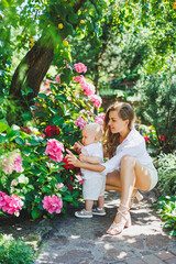 A young happy mother holds her one-year-old son in her arms during a walk. A loving mother hugs her son.