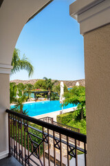 Side view from balcony showing garden and swimming pool. Lush greenery surrounds pool area, creating inviting and tranquil outdoor space. Balcony offers expansive view, highlighting garden and pool
