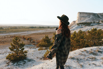Naklejka premium Woman in plaid shirt and hat enjoying scenic valley view from hilltop perch