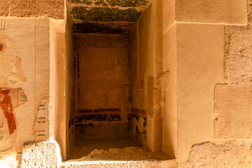 A narrow, dimly lit passageway leads to a hidden chamber within the temple of Hatshepsut....