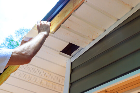 Plastic soffit boards are mounted to roof rafters of house ceiling