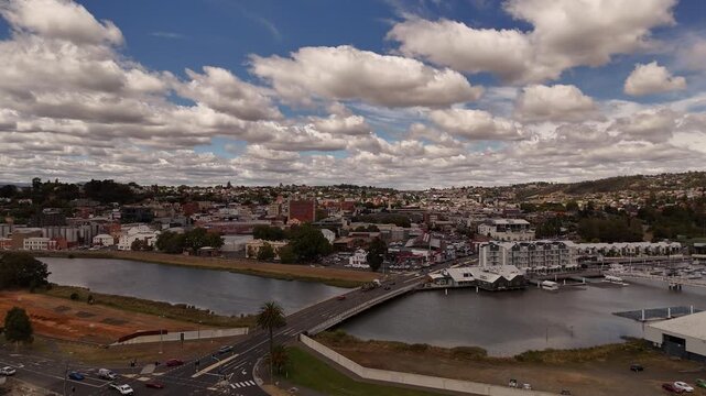 Aerial view over cloudy sky in North Launceston City area with river and bridge, Tasmania. Orbit wide shot of cityscape with Australian neighborhood.