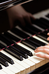 Fototapeta premium Female Pianist's Hands Gracefully Playing the Piano Keys in a Dimly Lit Room