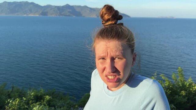 young woman afraid of heights, looking down in mountains