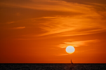 Segelboot vor der untergehenden Sonne und einem atemberaubenden Himmel