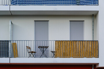 A balcony with a chair and table on it, minimalist photo of a balcony photographed from the sidewalk, minimal, front view