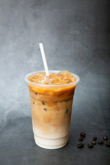 Iced latte coffee on plastic glass and tube-sucking on back marble background, summer drink concept...