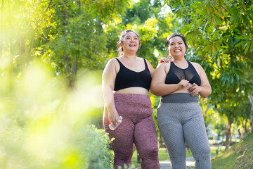 LGBTQ couple.Two smiling sporty young chubby overweight women in sportswear walking in park after...