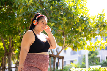 sportswoman listening music through headphones. beautiful young chubby overweight woman in...