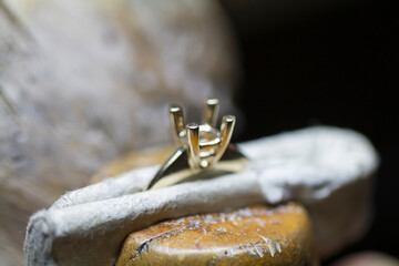 Macro shot of a goldsmith's hands at work on a diamond ring.