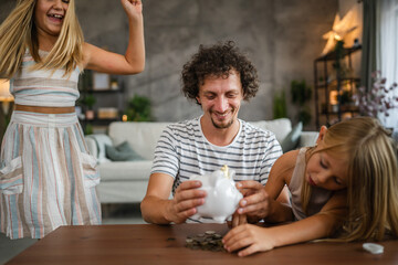 Father with daughters save coins, money in the piggy bank at home