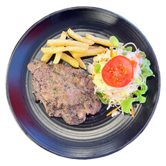 Grilled beef steak served with crispy French fries and fresh vegetable salad topped with tomato on a black ceramic plate, isolated on white background. Perfect meal concept for food