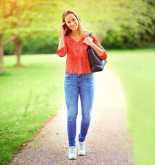 Woman, walking and portrait on park path, outdoor and eco friendly travel on weekend break in nature. Happiness, smile and holiday in summer for relax, peace and outside for journey with greenery