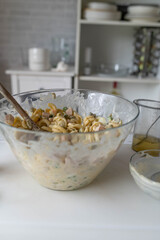 Traditional german pasta salad fresh prepared in the kitchen with mayonnaise, pickles, sausage, green peas and eggs in a bowl